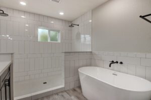 A bathroom with white tile and wood floors.