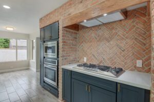 A kitchen with brick walls and blue cabinets.