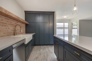 A kitchen with dark cabinets and white counters.