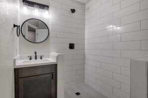 A bathroom with white tile and black accents.