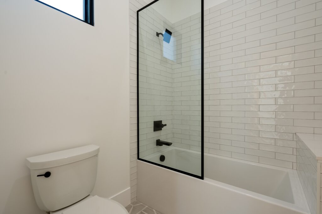 A bathroom with a tub, toilet and shower.