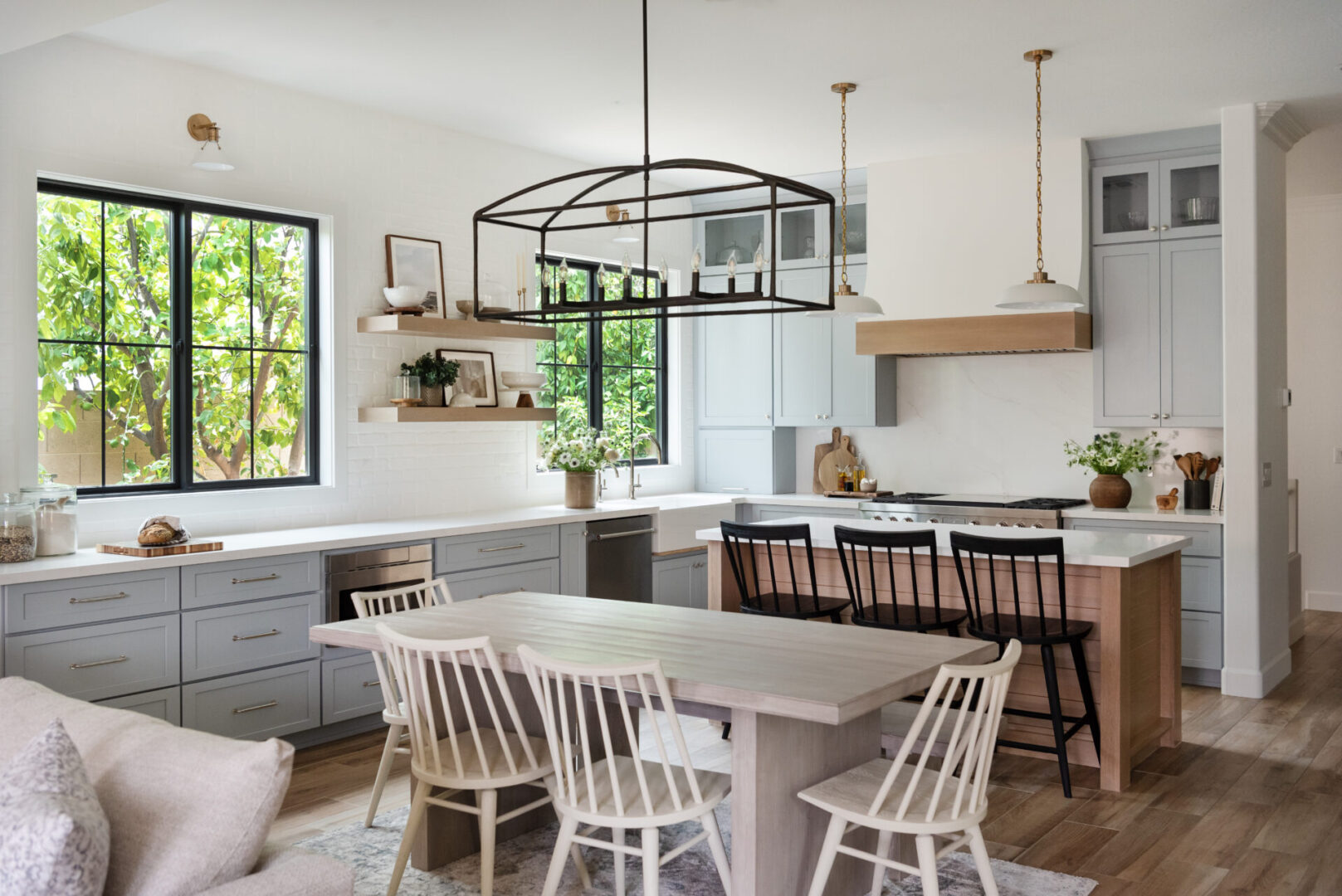 Builders Flooring & Design project gallery modern farmhouse kitchen with light blue and white painted cabinets and wood trimmed hood and open shelves.