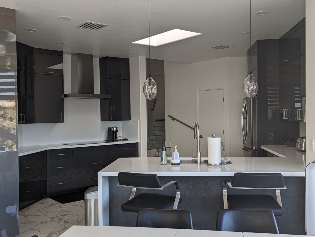 A kitchen with black cabinets and white counters.