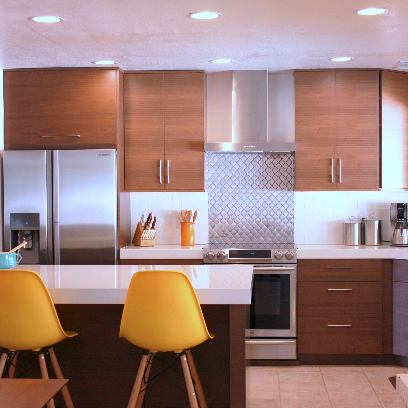 A kitchen with three yellow chairs and a stove.