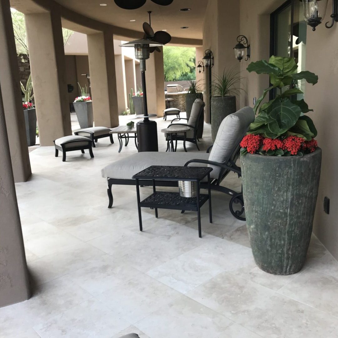 A patio with chairs and tables, potted plants.