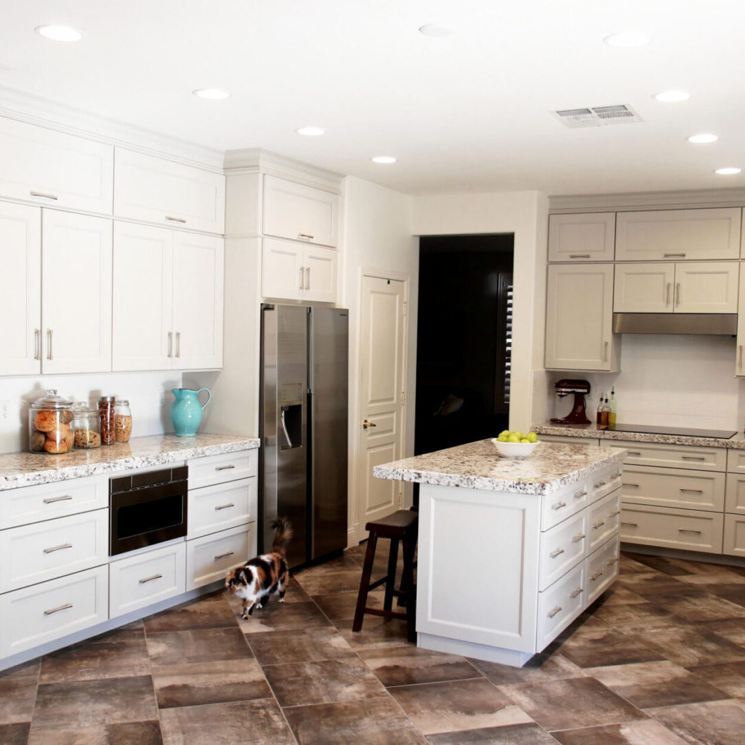 A kitchen with white cabinets and tiled floors.