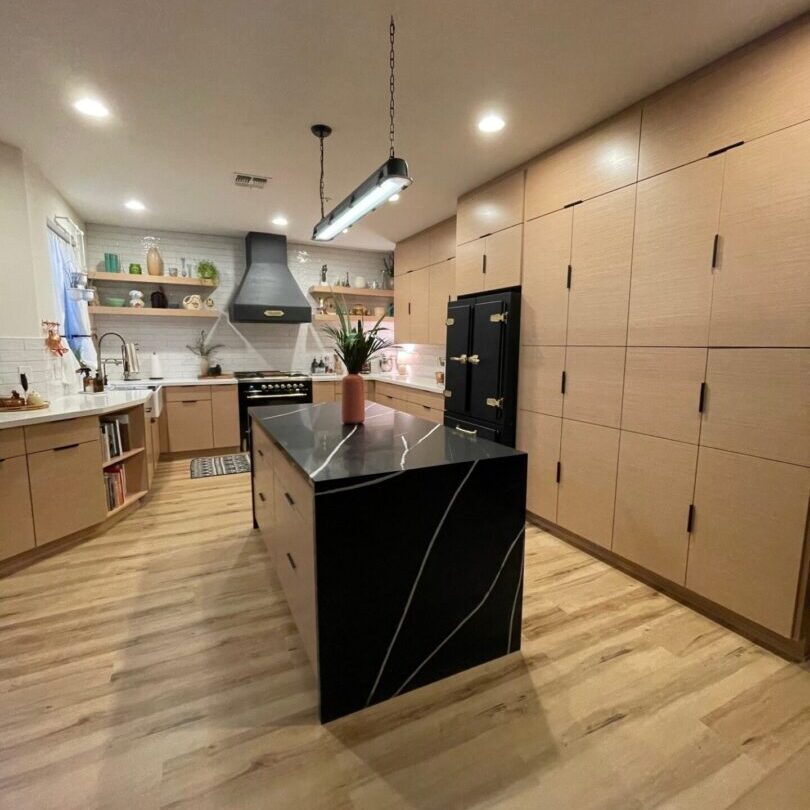 A kitchen with wooden floors and black counter tops.