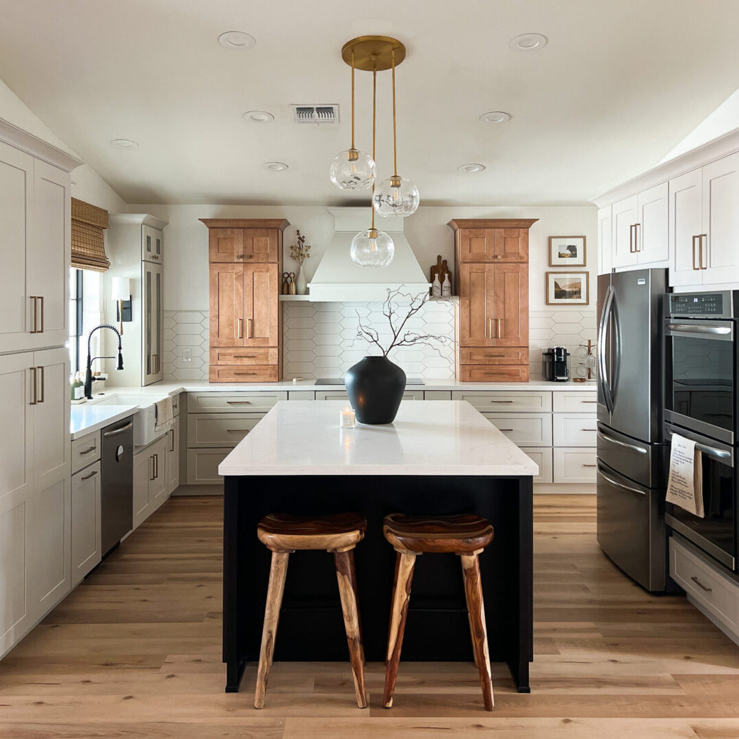 A kitchen with white cabinets and black island.