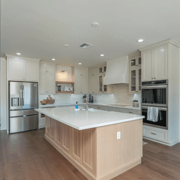 A kitchen with white cabinets and wood floors.