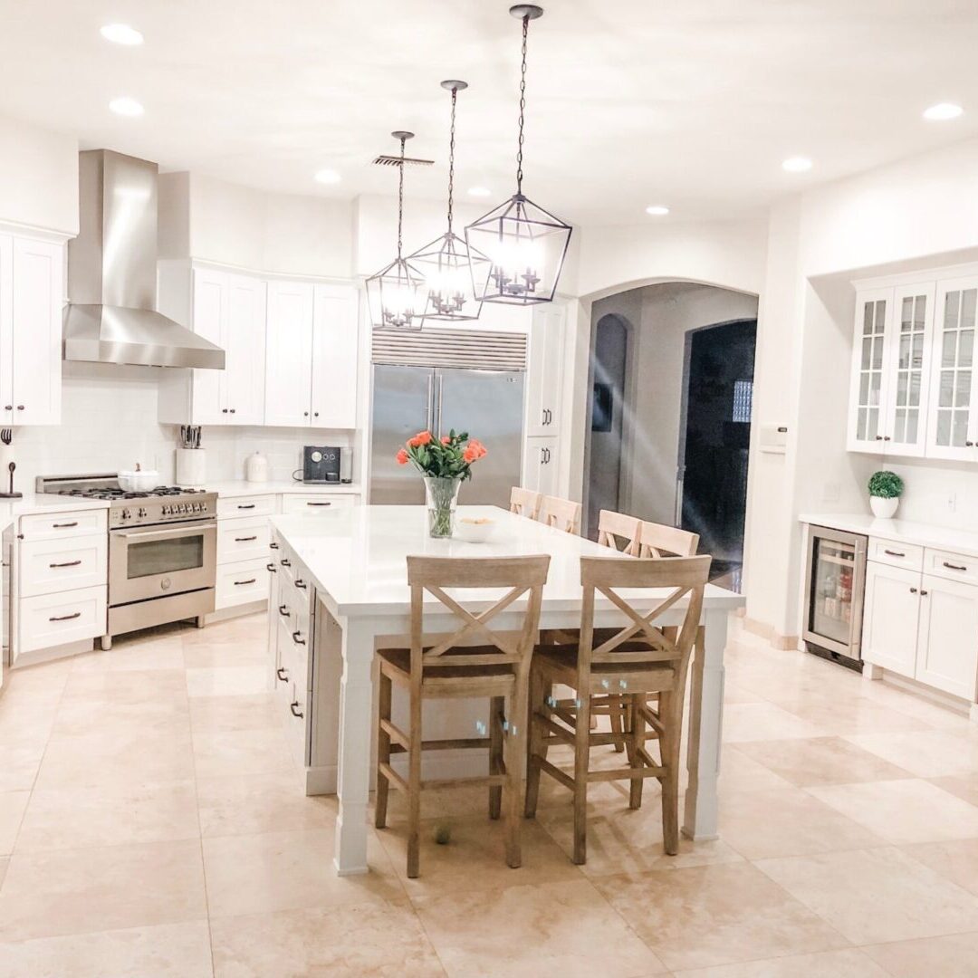 A kitchen with white cabinets and tile floors.