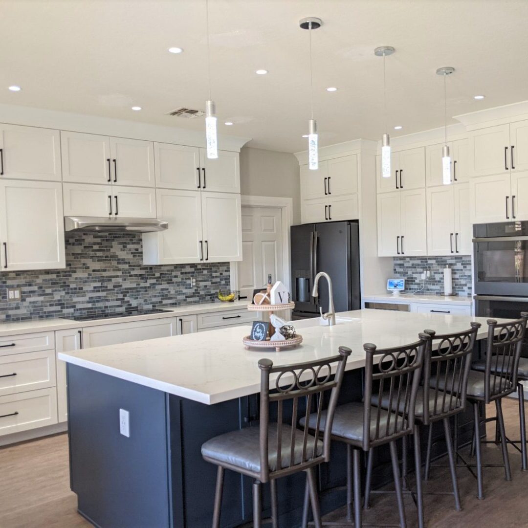 A large kitchen with white cabinets and black island.