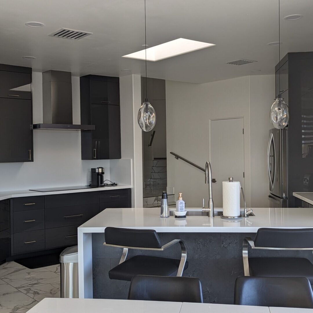 A kitchen with black cabinets and white counters.