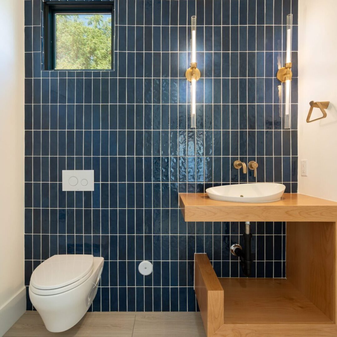 Unique bathroom vanity with modern styling and stacked vertical blue subway tile outlined in white grout accenting geometric lines.