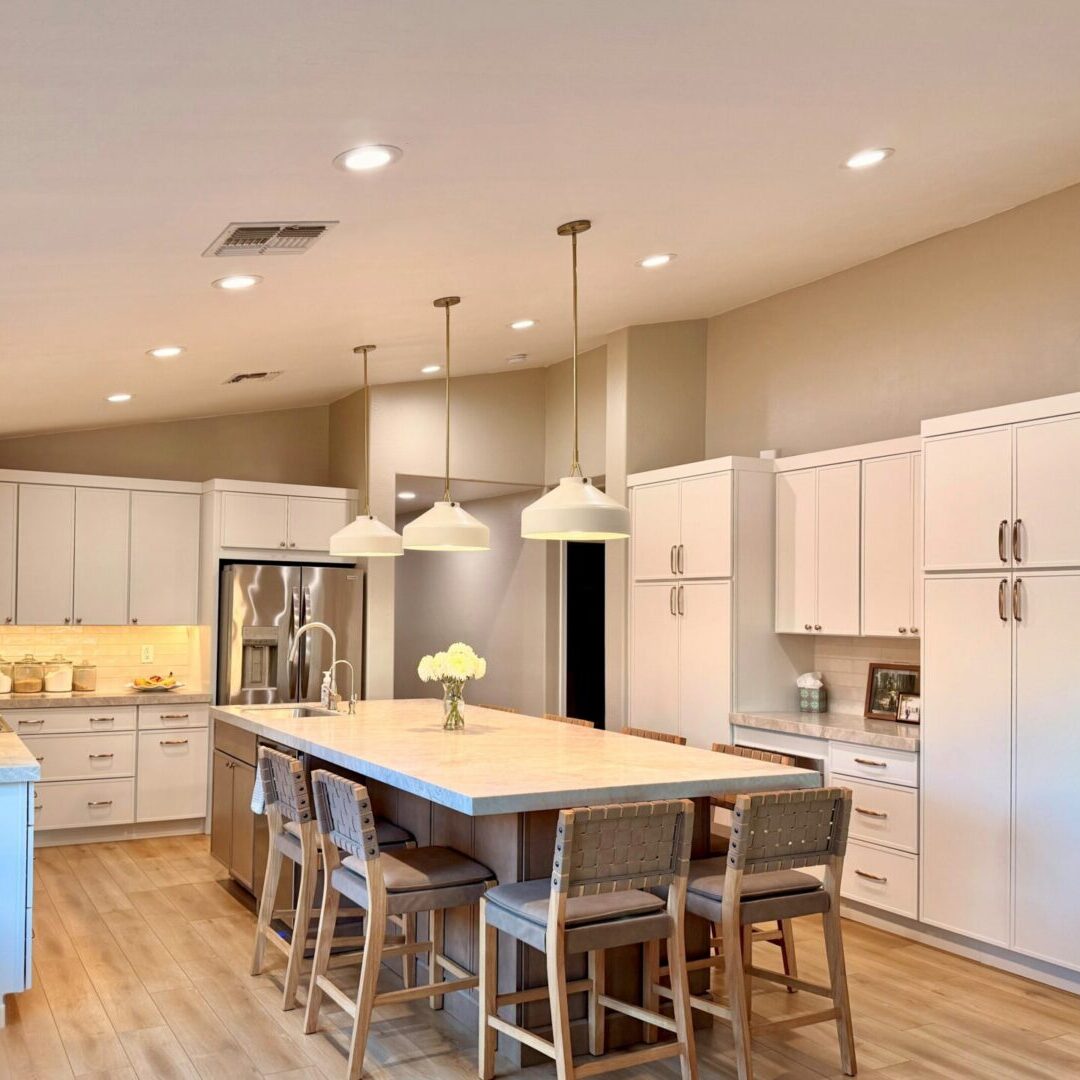 A kitchen with white cabinets and wooden floors.