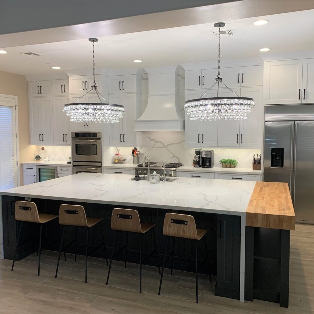 A large kitchen with white cabinets and black island.