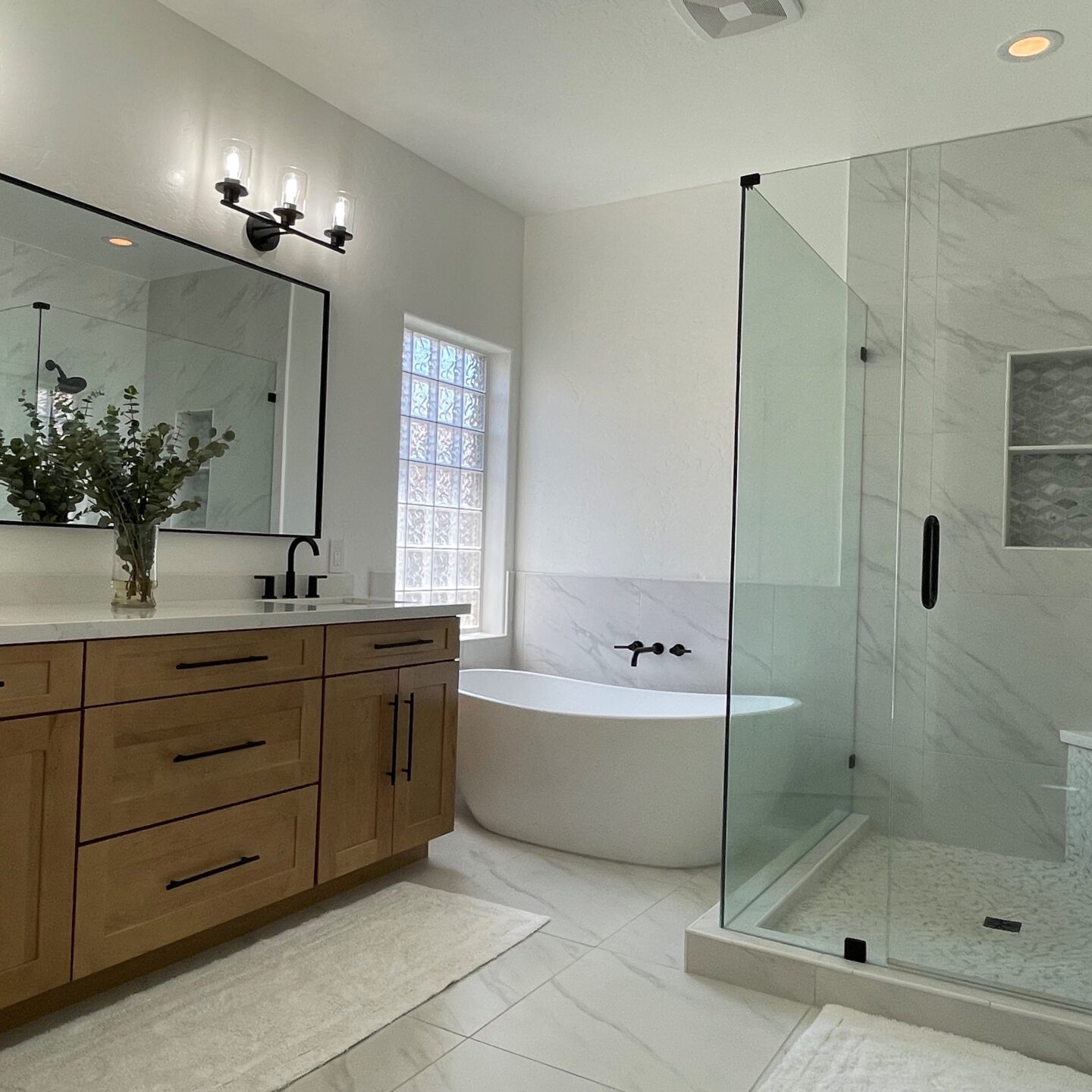 A bathroom with a large glass shower and a tub.